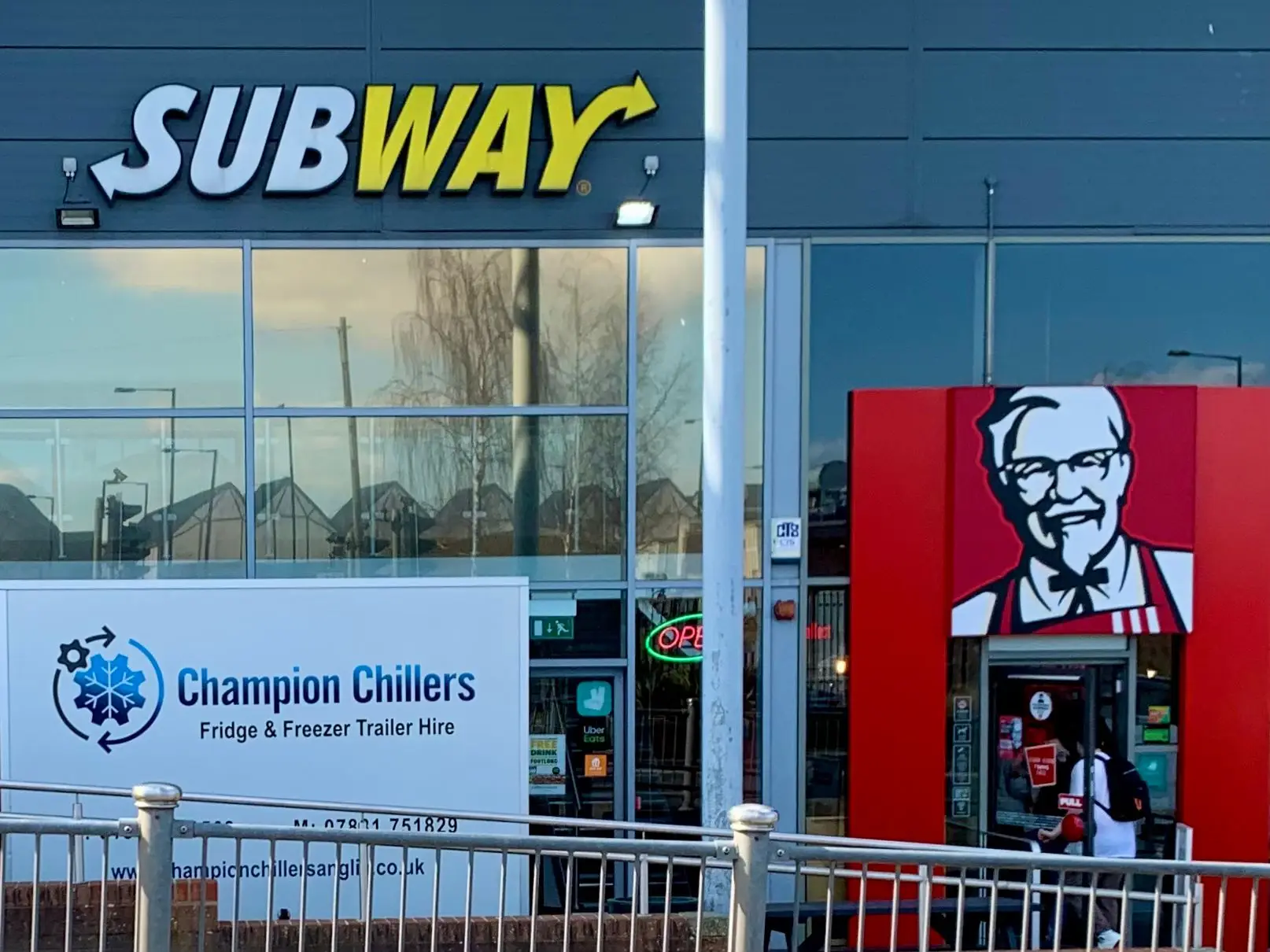 Champion Chillers fridge and freezer trailer hire signage outside Subway and KFC units on a retail parade.