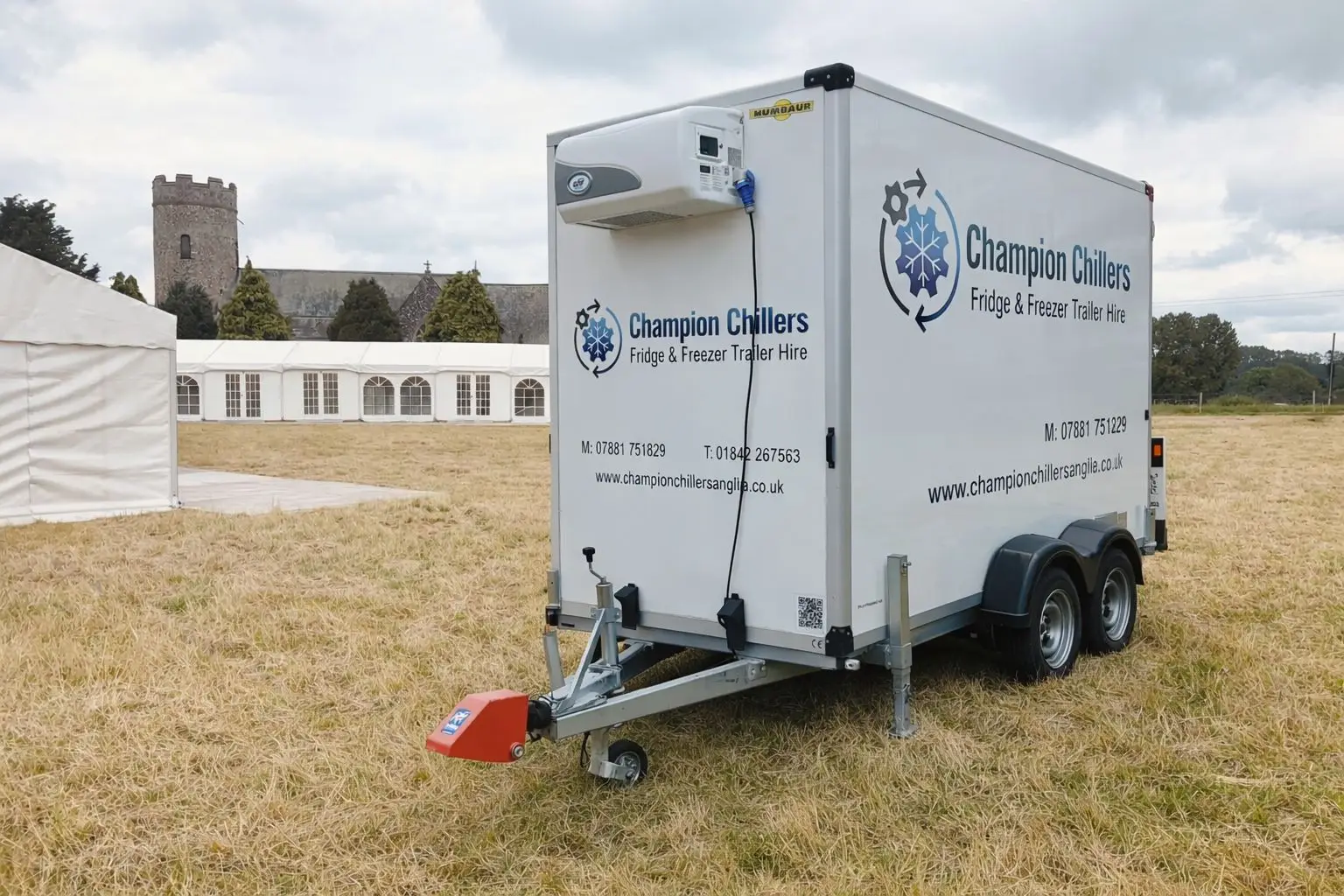 Champion Chillers fridge and freezer trailer hire unit set up on grass beside marquees at an outdoor event.