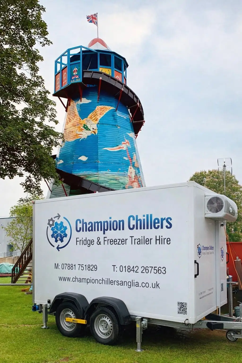 Champion Chillers fridge and freezer trailer hire unit parked on grass beside a painted helter-skelter tower at a fair.