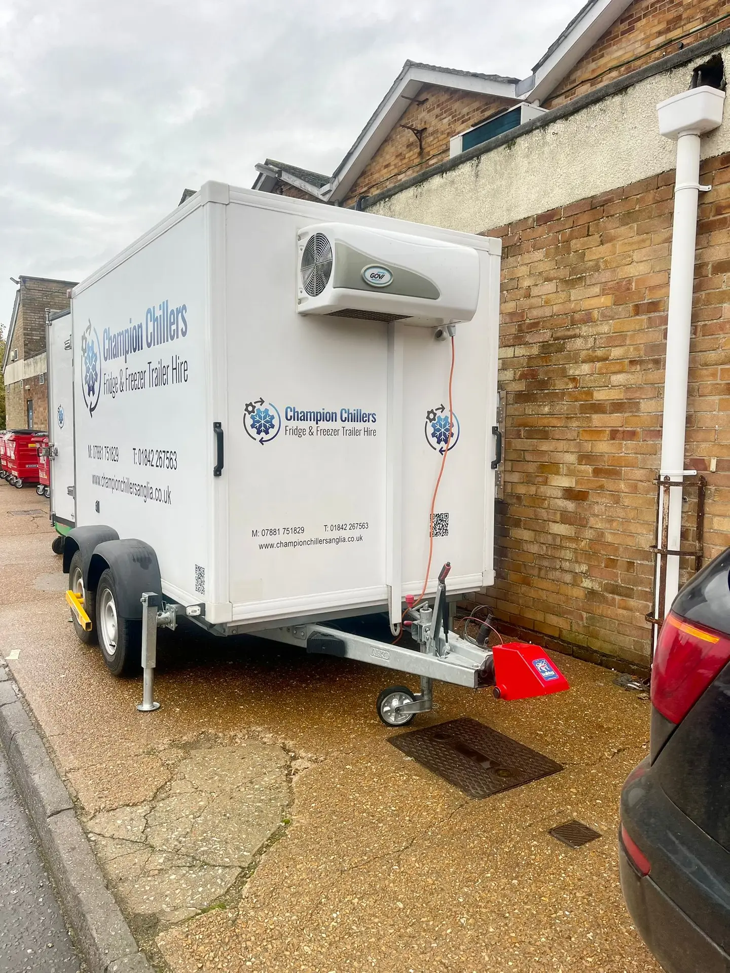 Champion Chillers fridge and freezer trailer hire unit parked in a rear service yard behind commercial buildings.