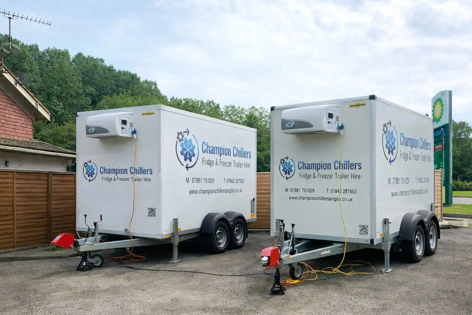 Two Champion Chillers fridge and freezer trailer hire units parked side by side on a gravel yard.